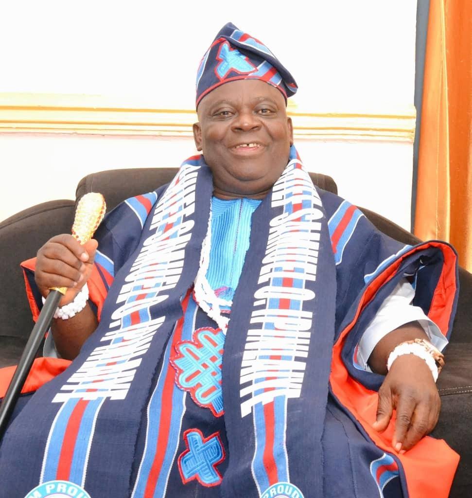 Amb. Chief Samuel O. Ipinlaiye adorned in traditional Takete-Ide woven regalia and sash holding ceremonial staff.